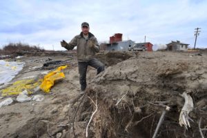 一名暴风雨保护工人站在阿拉斯加纳帕基亚克的Yupik Eskimo村的岸边，在那里永久性融化导致侵蚀和洪水。当地领导人正在考虑搬迁村庄。