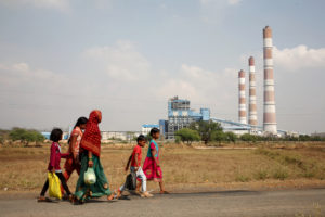 女人和孩子走过一个火力发电厂在恰蒂斯加尔邦,印度。