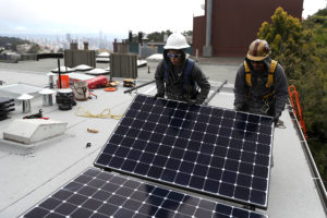 工人在旧金山的一所房屋上安装太阳能电池板，该房屋对在新建筑中使用天然气的使用受到限制。