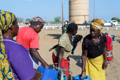 在纳米比亚卡万戈地区的一个公共饮用水箱中的妇女，那里的水很少。