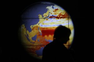 2015年12月，在巴黎举行的气候谈判中，一名妇女走过一张显示过去22年海平面变化的地图