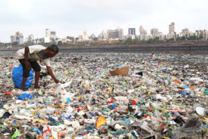 一个“拾荒者”在孟买的海岸线上，到处都是塑料垃圾。
