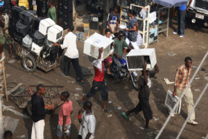 尼日利亚拉各斯的阿拉巴国际市场上，小贩们扛着旧空调。