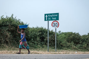 一个女孩走过翠鸟油田的标志在乌干达湖附近在1月份。
