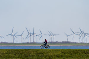 德国诺德尼，一名骑自行车的人在风力涡轮机前的堤坝上。