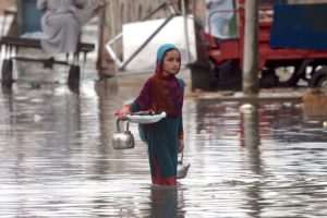 一个巴基斯坦女孩携带家庭财产通过2020年8月在卡拉奇被淹没的街道。