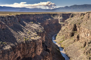 的里奥格兰德河流经陶斯峡谷上个月在新墨西哥州,小腿峡谷/隐士峰火燃烧在远处。