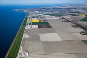 堤,绿色的沿岸地带,保护花字段和风力涡轮机在荷兰北部。