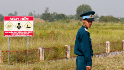 去年10月，在Bien HOA空军基地，一名越南士兵旁边是二恶英污染的危险警告标志。