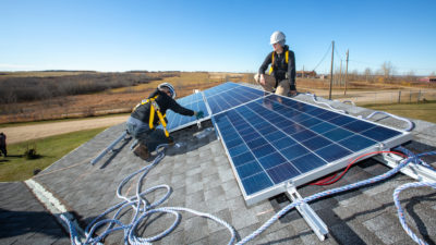 前焦油沙子工人在艾伯塔省韦维斯基威文州的儿童保育中心安装太阳能电池板。