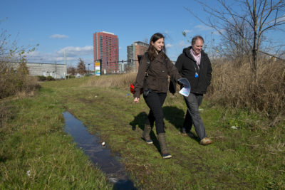 城市规划师利亚Kacanda和布莱恩·列侬,威明顿的水,走进一个湿地区域,很快就会被一个新公园的一部分,减轻洪水灾害自然项目。