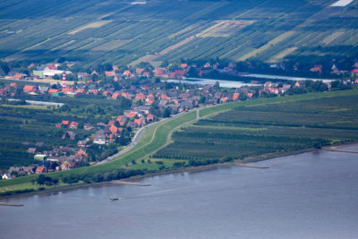 一条堤坝保护着汉堡下游的一个村庄。一些人提议，农业区域，比如果园，应该在高水位时为洪水开放。