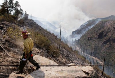 2011年7月，拉斯康查斯大火期间，洛斯阿拉莫斯峡谷上空的一名消防员。最严重的时候，这场大火每秒烧毁了近一英亩的森林。