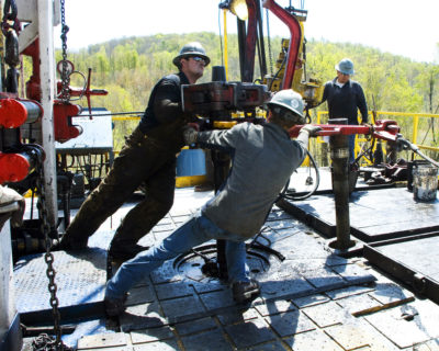 工人在宾夕法尼亚州伯灵顿附近的切萨皮克能源天然气场所将一部分井外套管移至适当的位置。