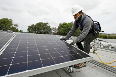 在Coronavirus爆发中，一名工人在海沃德的房子安装太阳能电池板。