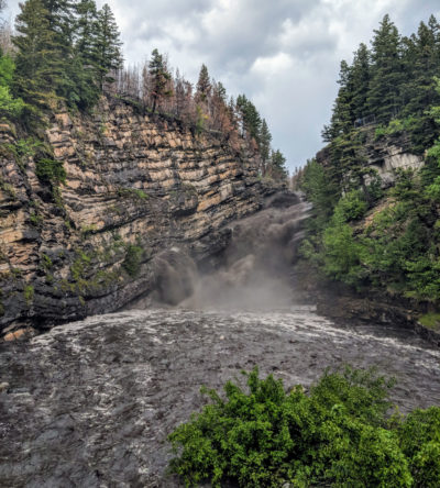 卡梅伦瀑布用烟灰和烧焦的碎片在6月21日，一年后，在艾伯塔省沃特顿国家公园烧毁火灾后一年。