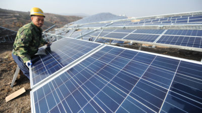 山东烟台，一名中国工人在太阳能农场安装太阳能电池板。