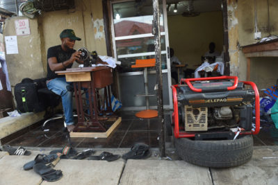 在拉各斯，一名裁缝正在使用一台发电机作为备用电力。由于不断增长的能源需求使尼日利亚有限的电力供应紧张，这座城市经常停电。