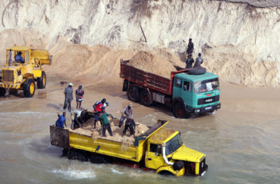 卡车沿着达喀尔北部的海滩装载非法开采的海砂，为塞内加尔的建筑业提供物资。