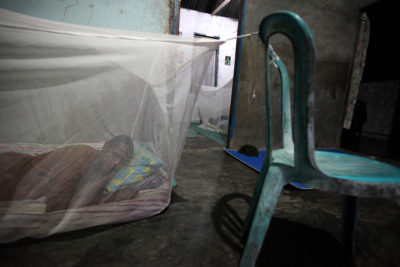 一个男人在他的家在西巴布亚，印度尼西亚的家里睡觉在蚊帐里面。