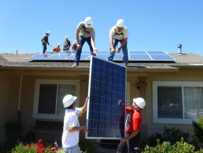 工人们在加利福尼亚州洛斯阿拉莫斯一户低收入家庭的房子上安装太阳能电池板。
