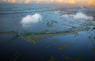 让·查尔斯岛(Isle de Jean Charles)——或者说是它的剩余部分——是一个位于1.5英里长的狭长地带上的由房屋组成的小飞地。随着南路易斯安那湿地继续下沉，海平面继续上升，这个岛屿已经成为一个脆弱的环境前哨站被低矮的堤坝包围。
