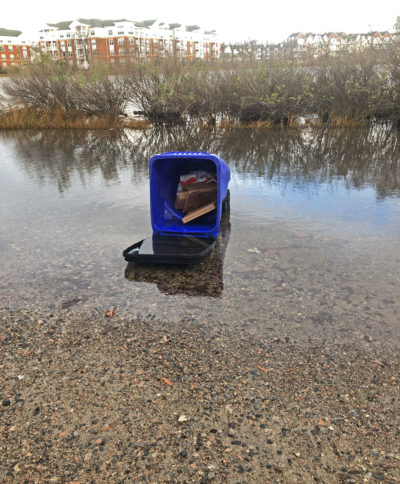 在维吉尼亚州诺福克52街，一个翻倒的垃圾桶被淹没在涨潮的洪水中。
